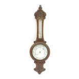 An aneroid barometer with carved oak decoration. 36" high Please Note - we do not make reference
