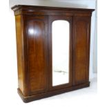 A Victorian mahogany triple wardrobe with a moulded cornice above a central mirrored door and two