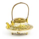 A small Japanese Satsuma sake or tea pot of squat form raised on three feet, decorated with