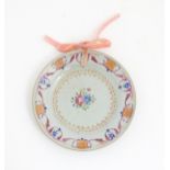 A small Chinese famille rose plate decorated with central floral detail and scrolling borders.