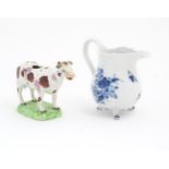 A Swansea cow creamer. Together with a Continental blue and white three footed jug decorated with