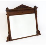 An Aesthetic movement mahogany mirror with a carved pointed pediment above fluted and floral