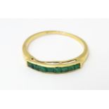 A gold ring set with band of emeralds. Ring size approx. Q Please Note - we do not make reference to