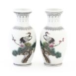 A pair of Chinese vases each decorated with a crane bird perched in a pine tree with flowers. The
