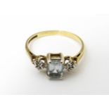 A 9ct gold ring set with central aquamarine flanked by illusion set diamonds. Ring size approx. I