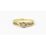 A 9ct gold ring set with central diamond flanked by four further diamonds to each shoulder. Ring