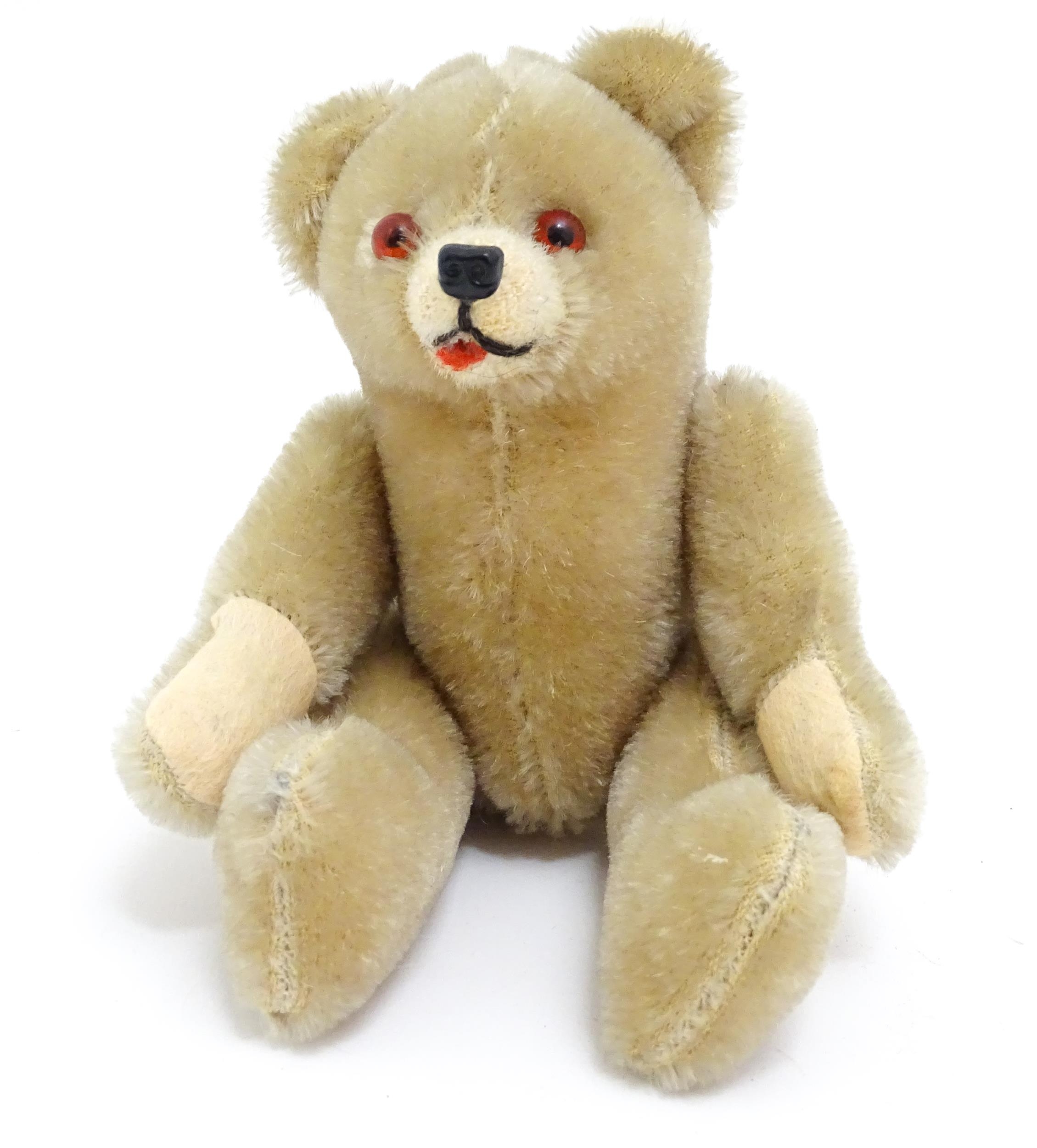 Toy: A small 20thC plush teddy bear with stitched mouth, fabric tongue, pad paws and articulated