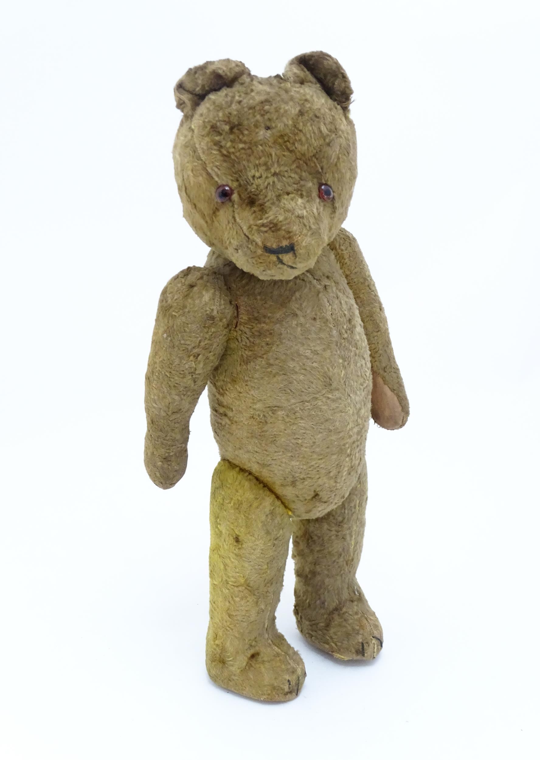 Toy: An early 20thC straw filled teddy bear with stitched nose, mouth and claws, glass eyes, pad