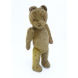 Toy: An early 20thC straw filled teddy bear with stitched nose, mouth and claws, glass eyes, pad
