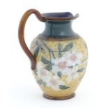 A Doulton Lambeth Art Union of London stoneware jug decorated with flowers and foliage in relief.