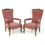 A pair of 19thC rosewood library chairs with carved cresting rails above buttoned backrests and