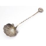 A Victorian silver preserve / sugar spoon with scallop shell formed bowl and handle finial.
