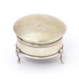 A silver ring box of circular form with hinged lid and raised on three feet. Hallmarked Birmingham