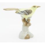 A Royal Dux model of a yellow bird perched on a branch with pine cones. Marked under. Approx. 6"