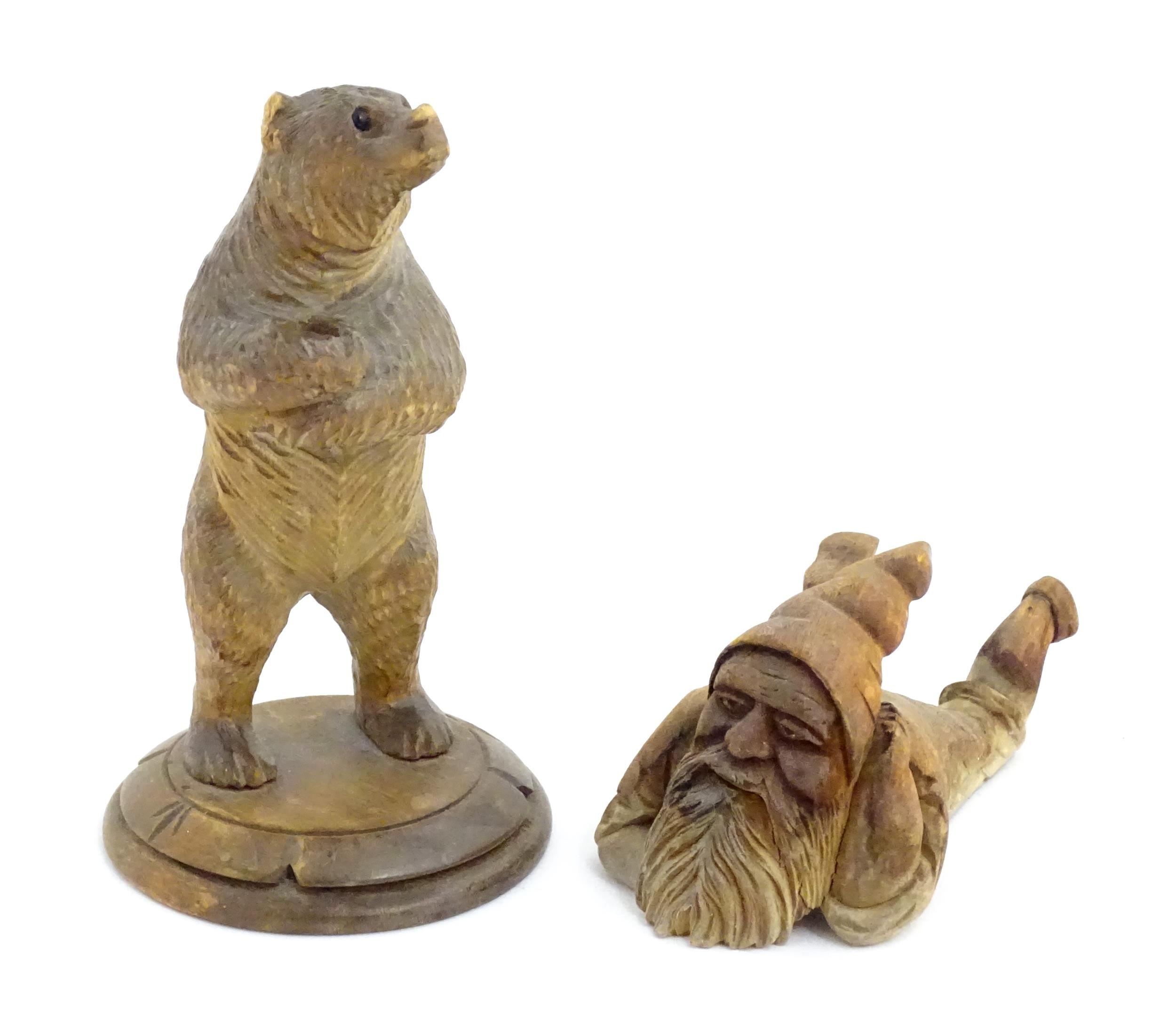 A 20thC Black Forest carved model of a bear. Together with a carved model of a recumbent gnome.