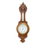 A 20thC aneroid barometer surmounted by thermometer within a carved wooden surround. Approx. 30"