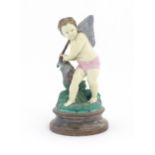 A Continental majolica style putto figure modelled as a fisherman with a net and basket of fish.