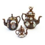 Three Victorian treacle glazed bargeware teapots. with applied flower and banner detail. The largest