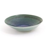 A studio pottery bowl by Mike / Michael Dixon with blue / green glaze and incised banded detail to