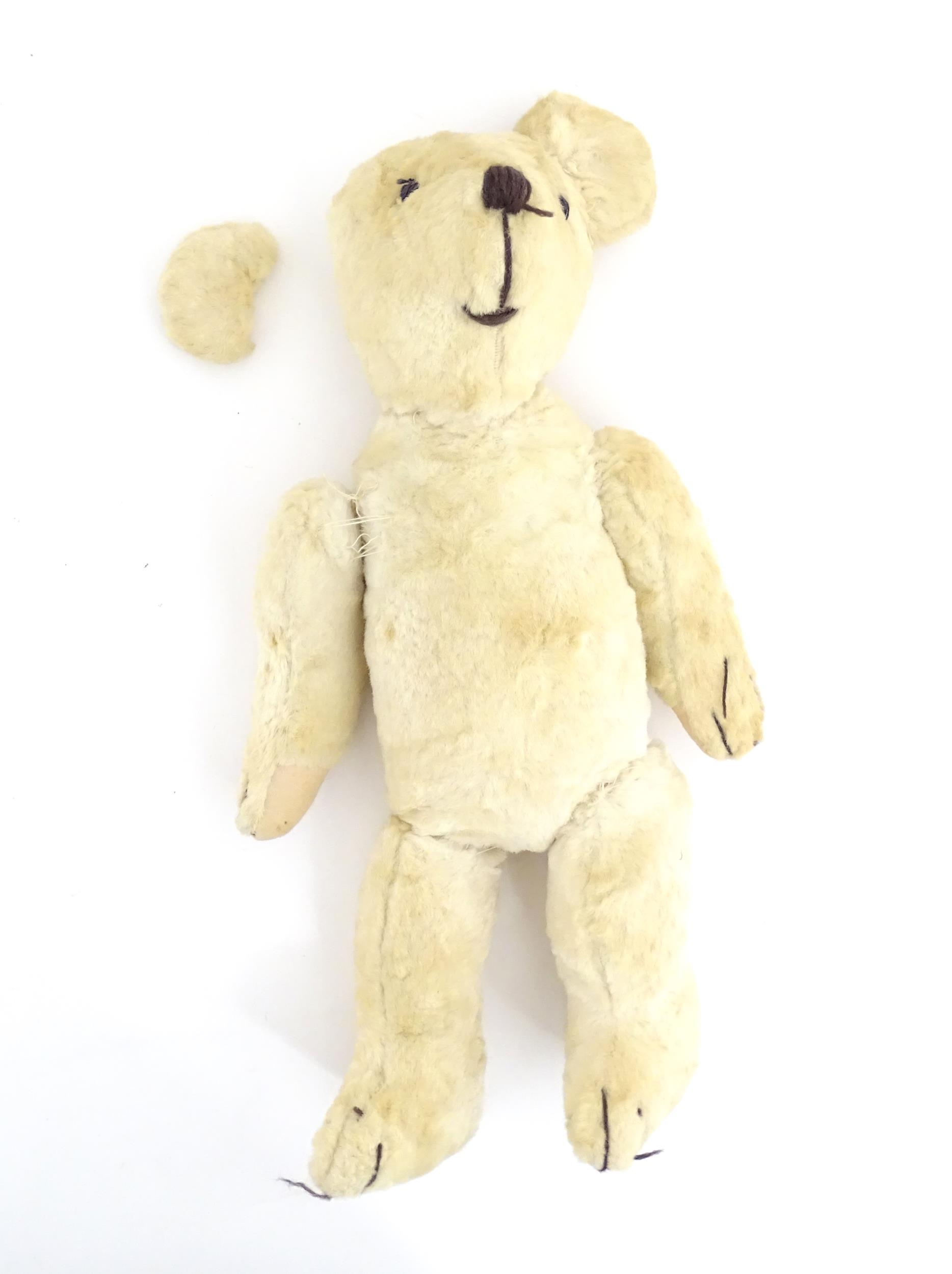 Toy: A 20thC plush teddy bear with stitched nose, mouth, eyes and paws. Approx. 19 1/2" long