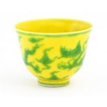 A Chinese wine cup the yellow ground decorated with green dragons and stylised clouds. Character