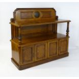 A late 19thC oak buffet, with a shaped upstand, carved edges, burr panels and carved roundel to