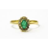 A gold ring set with central emerald bordered by diamonds. Ring size approx R Please Note - we do