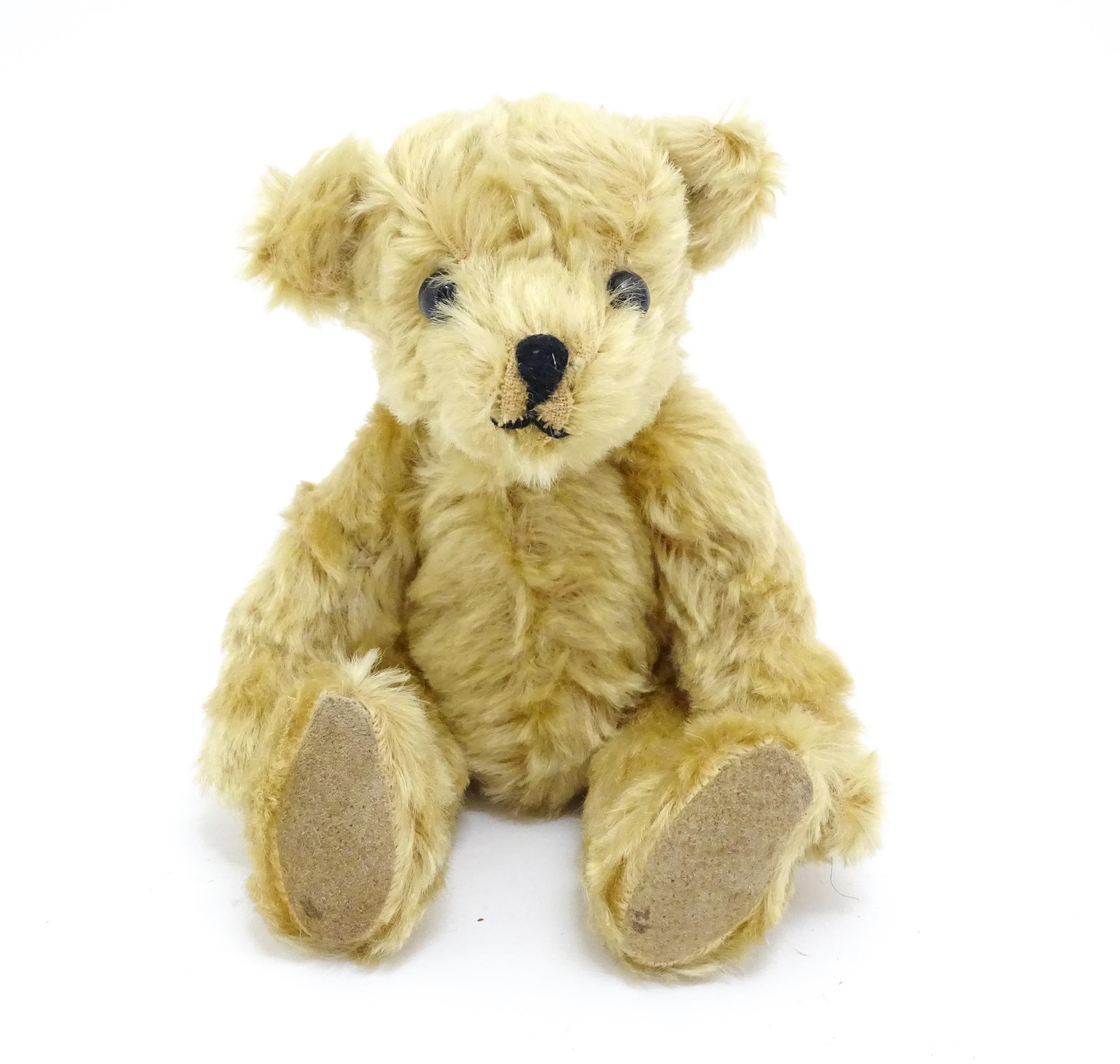 Toy: A 20thC small plush teddy bear with stitched nose and mouth, pad paws and articulated limbs,