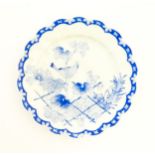 A Japanese blue and white plate with scalloped edge, decorated with a bird perched on a branch