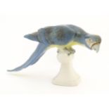 A Royal Dux model of a Macaw bird / Parrot with blue, green and yellow feathers perched on a finial.