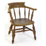 An early 20thC smokers bow armchair, with scrolled and a shaped seat raised on turned tapering