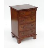 A mahogany veneered chest of drawers with a serpentine front and four short drawers raised on
