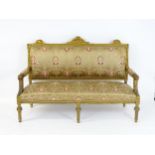 A late 20thC giltwood sofa with a floral carved frame, having an upholstered backrest, manchettes