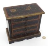 A painted model of a chest of drawers decorated with stars, sun and moon. Approx. 7 3/4" high Please