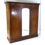 A Victorian mahogany triple wardrobe with a moulded cornice above a central mirrored door and two