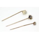 Three various gold and yellow metal stick pins including examples set with moonstone and a banded