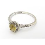 A 9ct white gold ring set with central citrine coloured stone bordered by diamonds and with