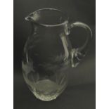 A glass jug with loop handle decorated with etched Alpine Ibex in landscape. Approx 10" high