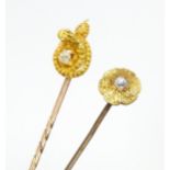 Two yellow metal and gilt metal stick pins set with diamonds, one entwined by a coiled snake with