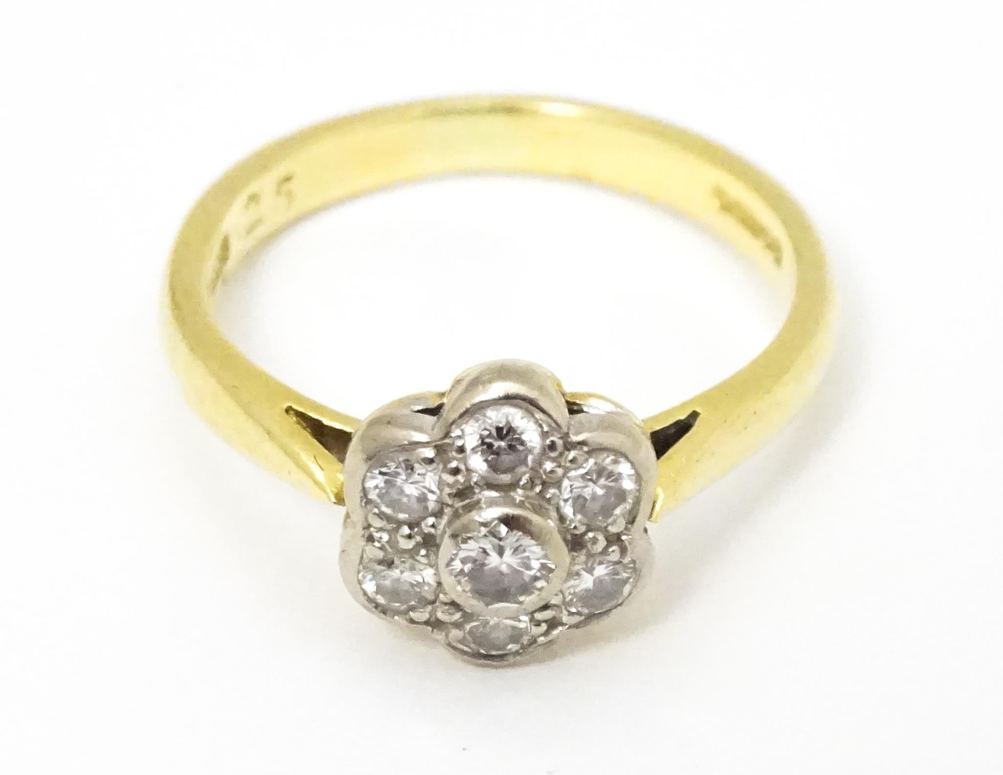 An 18ct gold ring set with 7 diamonds in a daisy setting. Ring size approx. H Please Note - we do