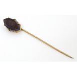 A yellow metal stick pin with carved intaglio to top. Approx 2 3/4" long Please Note - we do not