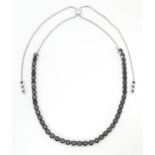 A silver slider necklace set with dark stones Please Note - we do not make reference to the