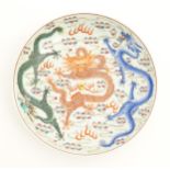 A Chinese famille rose plate decorated with three dragons and a flaming pearl amongst stylised