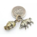 Three assorted charms to include a white metal model of a pig / boar, a buddha head and a coin fob
