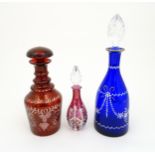 Three assorted glass decanters to include ruby, blue and cranberry coloured examples. The largest