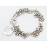 A silver bracelet with heart shaped fob engraved '.. Tiffany & Co...' The bracket approx 7 1/2" long