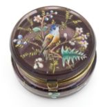 An amethyst coloured glass pot with hinged top having an painted scene of a bird amongst branches.