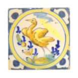 A Continental Delft style tile depicting a bird within a roundel, with shaped detail to corners.