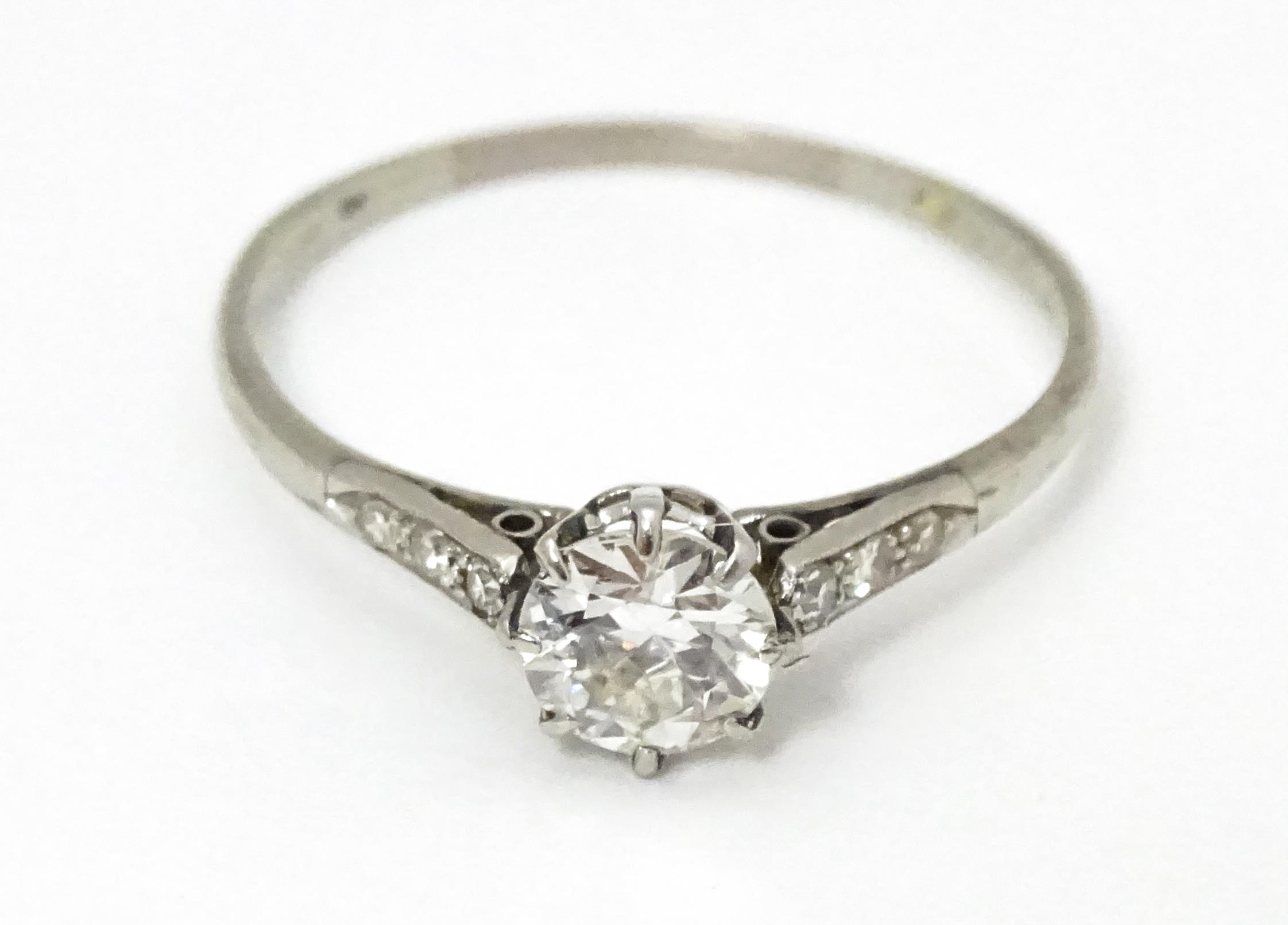 A 18ct white gold ring set with diamond solitaire ring flanked by 3 diamonds to the shoulders.