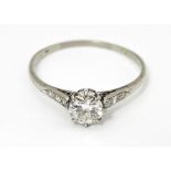 A 18ct white gold ring set with diamond solitaire ring flanked by 3 diamonds to the shoulders.